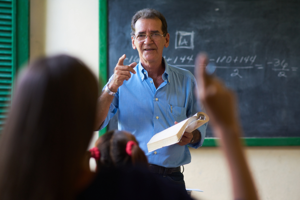 A teacher calls on a student as they raise their hand